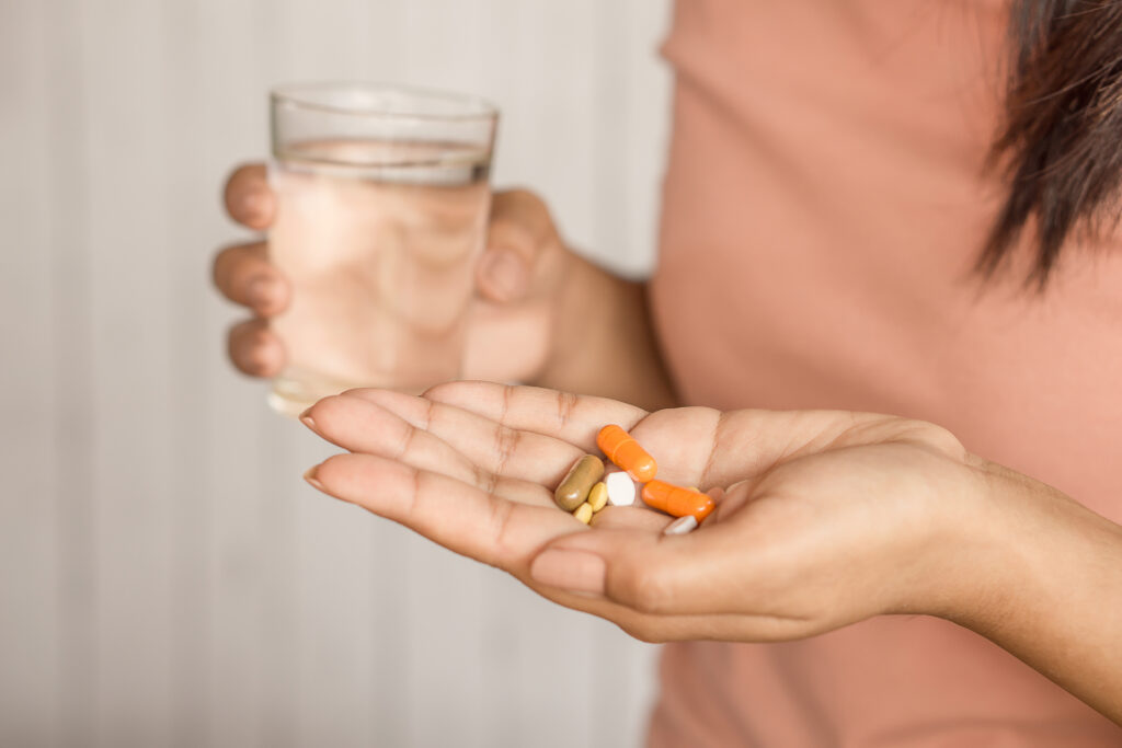 Fáradtság ellen vitaminokat és étrend-kiegészítőket szedő nő