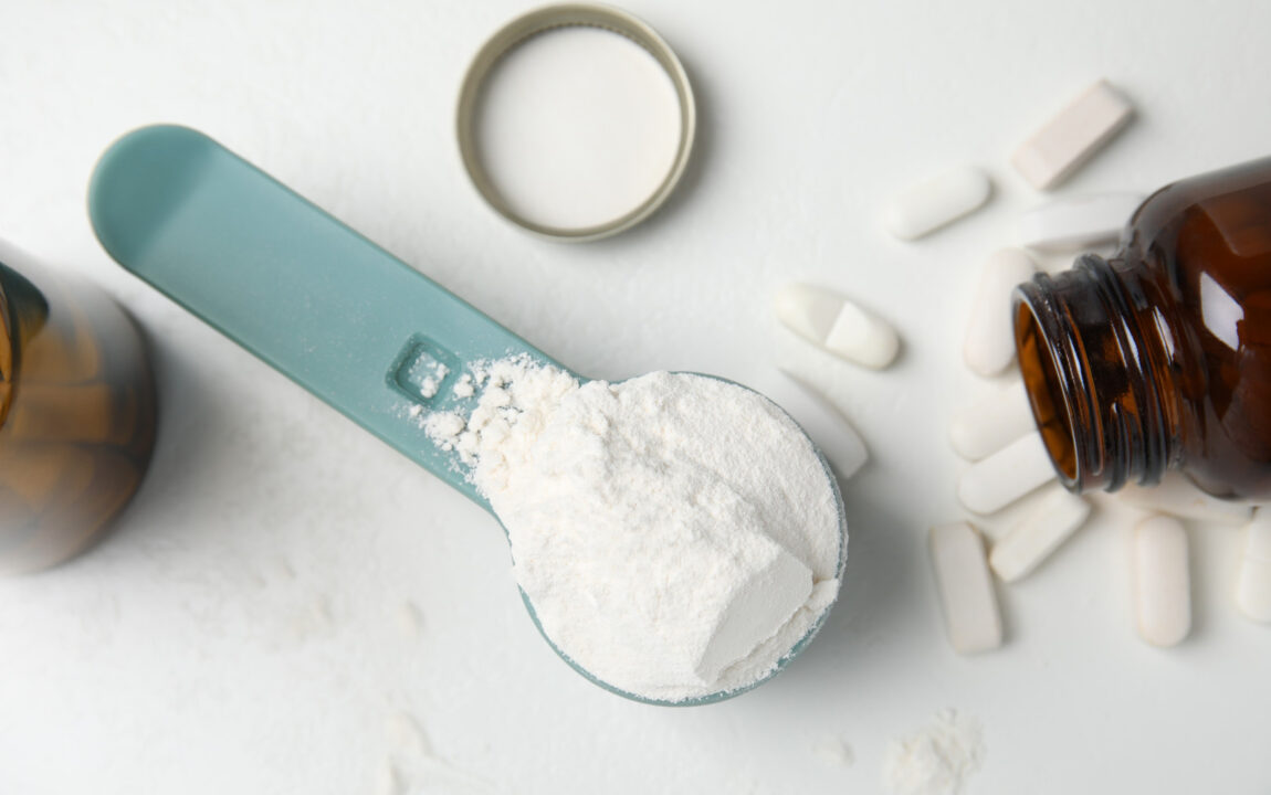 Adagolókanálban aminosav por és kapszulák fehér asztalon, táplálékkiegészítők a hirtelen fogyás ígéretével