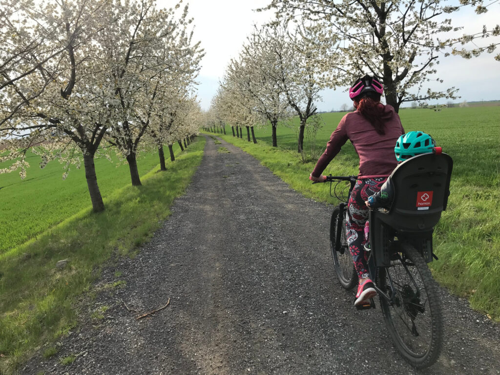 Mozgás tavasszal: nő kerékpározik virágzó fák között, könnyű szabadtéri sport kezdőknek